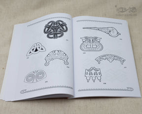 Book page displaying Viking ornamental designs focused on brooches, collars, and interlocking knotwork patterns rendered as detailed black line drawings