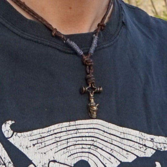 Vargkors halsband på man i naturomgivning, brunt läder med pärlad dekoration, korspendant med vargkors vänd nedåt