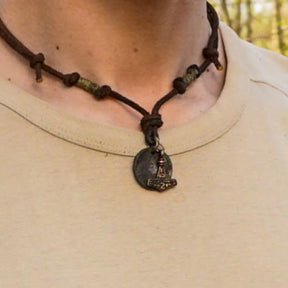 Halsband Enride bärat på person med ljus tröja, visar Torshammaren och myntet hängande från mörk läderband i naturlig miljö.